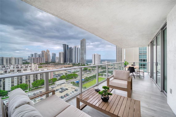Wide angle view of cityscape from a balcony with outdoor seating.