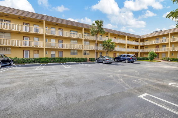 Front view of a three-story building with balconies and parking area.