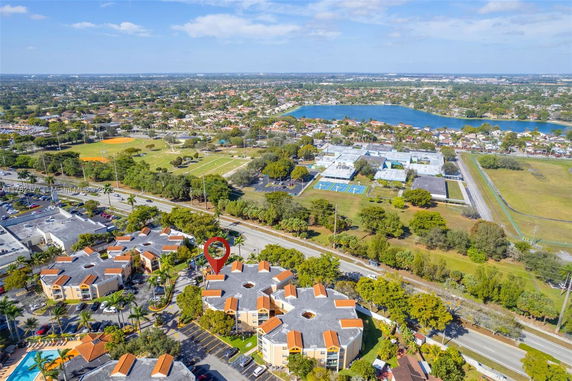 Aerial view of a residential area with multiple buildings, roads, and green spaces.