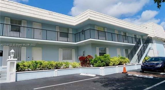 Front view of a two-story building with balconies and parking area.