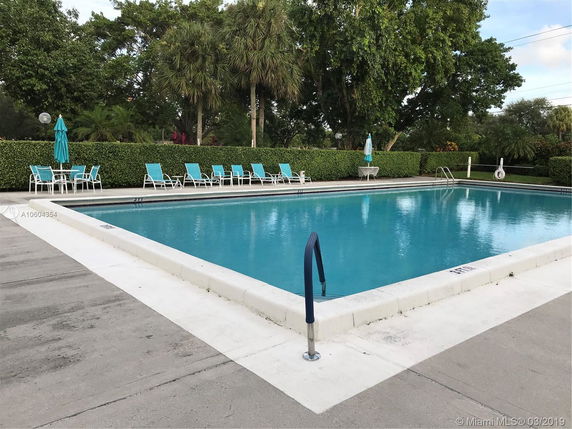 Outdoor swimming pool area with lounge chairs and umbrellas.