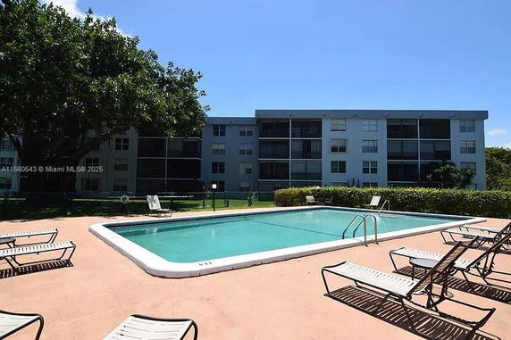 Outdoor swimming pool area in front of a multi-story residential building.