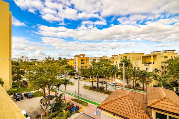 Elevated view of yellow residential buildings with roads and trees.