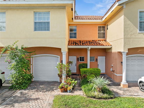 Front view of a two-story townhouse with a garage and a covered entrance.
