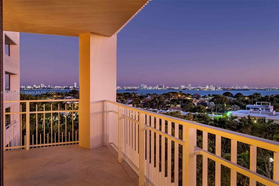 View from a balcony overlooking a cityscape and water at dusk.