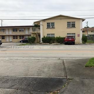 Front view of a two-story building with multiple windows and parked cars in front.