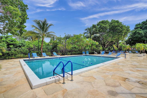 Outdoor swimming pool area with lounge chairs and surrounded by trees.