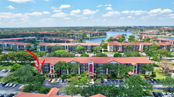 Aerial view of a residential complex with multiple red-roofed buildings and surrounding greenery.