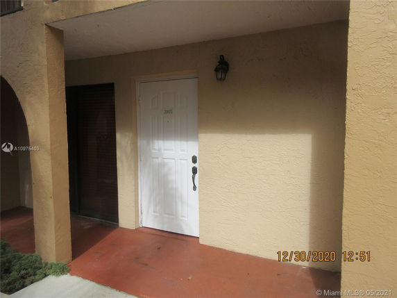 Front view of a building entrance with an arched doorway and a white door.