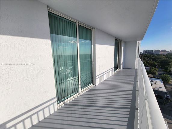 Outdoor balcony view with cityscape and ocean in the background.