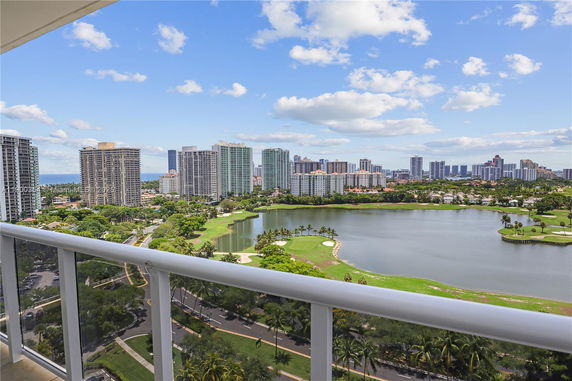 Panoramic view from a high-rise building overlooking a lake, golf course, and multiple high-rise buildings.