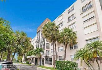 Front view of a multi-story residential building with palm trees.
