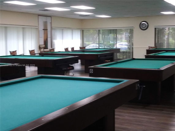Room with multiple billiard tables and chairs.