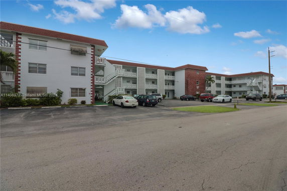Front view of a multi-story residential building with an adjacent parking area.