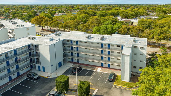 Aerial view of a multi-story building with flat rooftop featuring multiple air conditioning units.