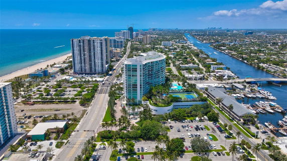 Aerial view of a coastal cityscape featuring high-rise buildings near the beach and a canal.