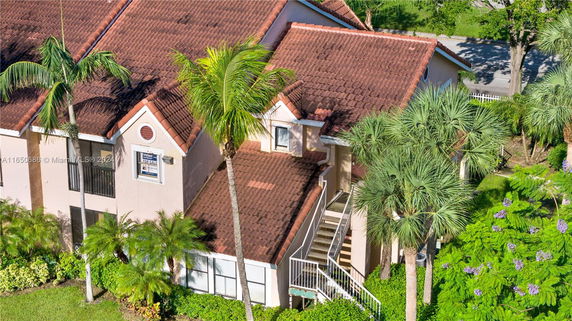 Front view of a two-story house with a red tile roof and exterior staircase.