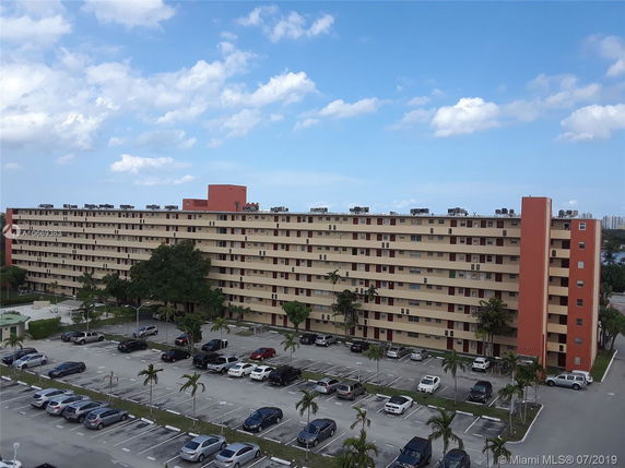Front view of a large multi-story apartment building with exterior corridors.
