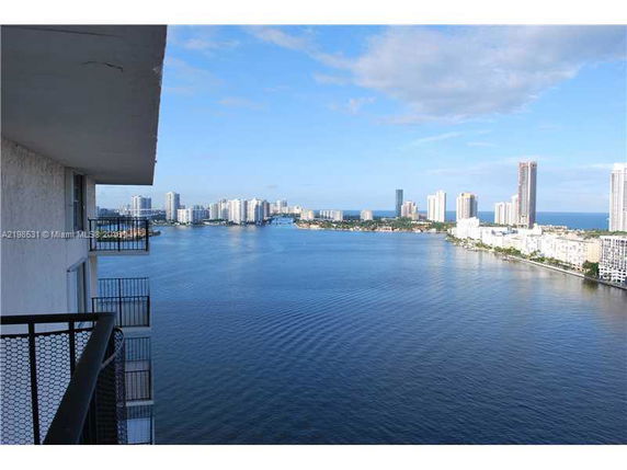 Panoramic view of city skyline and water body from a building balcony.