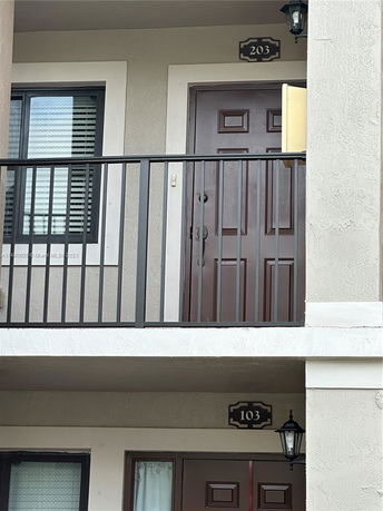 Front view of a multi-level apartment building showing doors numbered 203 and 103.