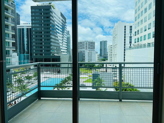 View from a balcony overlooking modern high-rise buildings and a swimming pool.