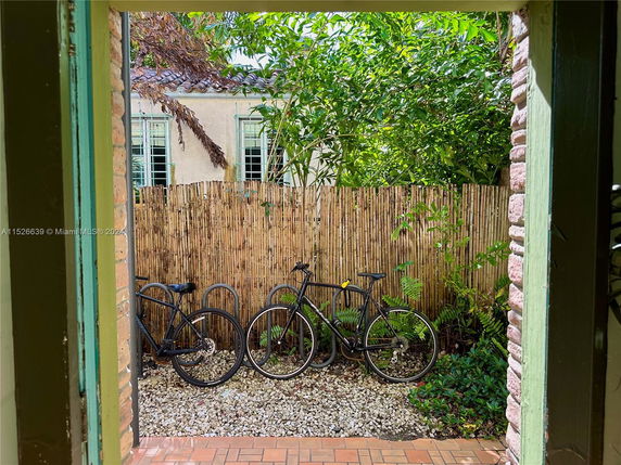 Bicycles parked outside near a bamboo fence with a view of a building facade.