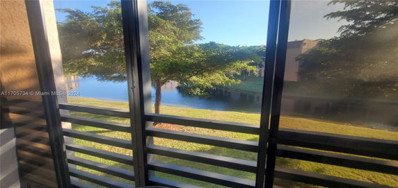 View from a building showing a tree and a water body outside.