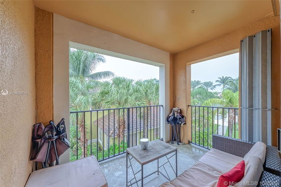 View from a balcony with outdoor furniture overlooking palm trees and rooftops.