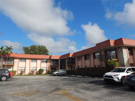 Front view of a two-story building with parking area and multiple cars parked.