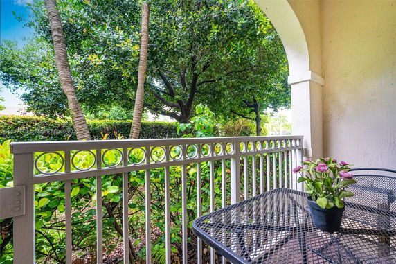 View from a covered patio area with railing, overlooking lush greenery and trees.
