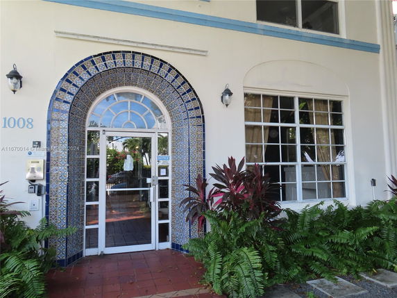 Front view of a building entrance with decorative tiles and large windows.