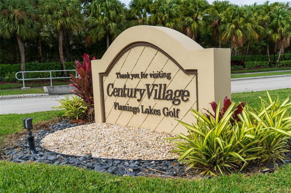 Signage for Century Village Flamingo Lakes Golf surrounded by landscaping.