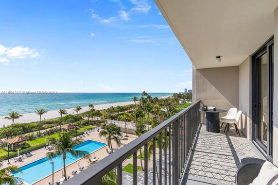 Panoramic view from a balcony showing a beach and swimming pool.