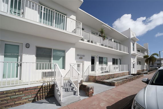 Front view of a two-story building with balconies and white railings.
