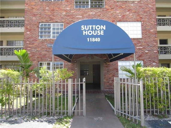Front view of a multi-story building with a blue awning entrance.