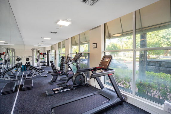 Indoor gym area with exercise equipment and large windows.