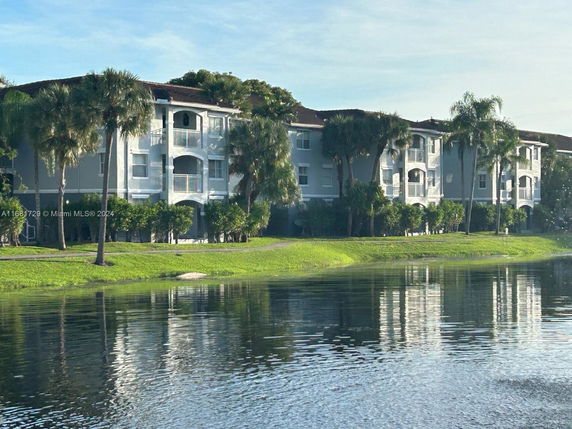View of a multi-story residential building with balconies near a water body.