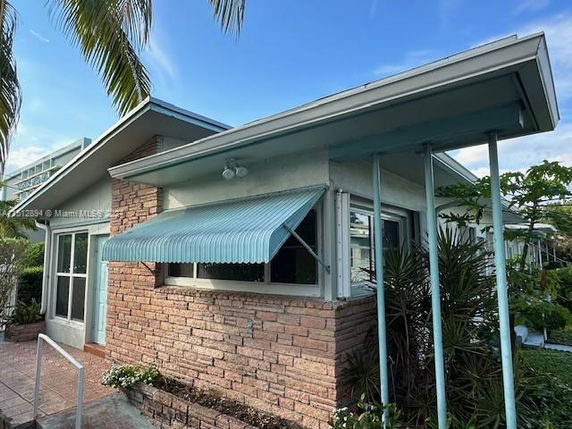 Front view of a house with a brick exterior and a blue awning.