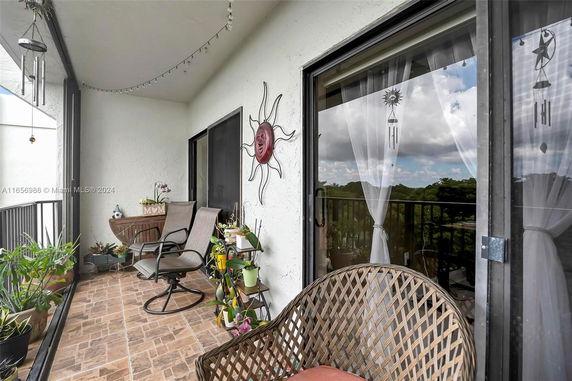 Balcony with seating area, plants, and decorative elements overlooking a landscape.