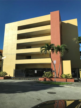 Front view of a multi-story apartment building with gated entrance and balconies.