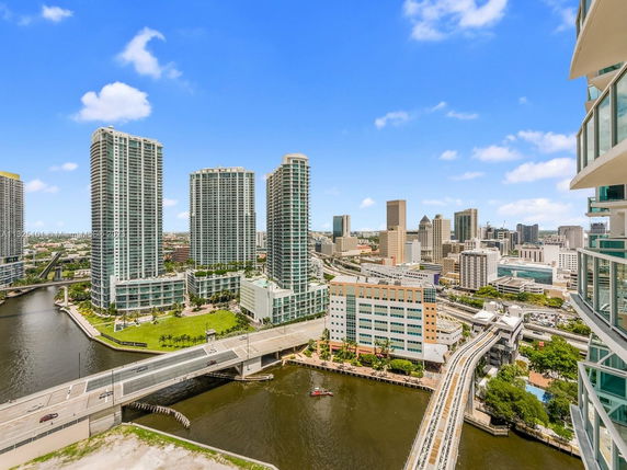 Panoramic view of high-rise buildings and a bridge over a river in a cityscape.