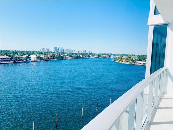 Panoramic view from a balcony overlooking a body of water and distant city skyline.