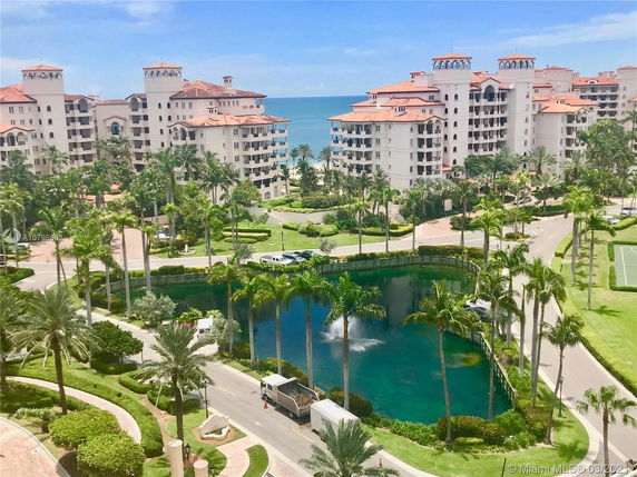 Distant view of a cluster of large multi-story residential buildings with red-tiled roofs near the ocean.