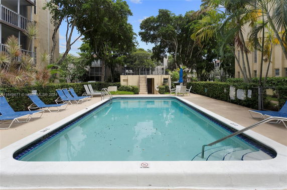 Outdoor swimming pool with lounge chairs and surrounding foliage.