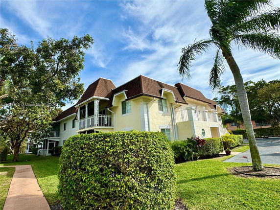 Front view of a two-story house with balconies and a brown roof.