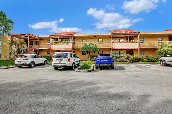 Front view of a two-story building with balconies and parking area.