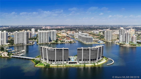 Aerial view of a waterfront cityscape featuring modern high-rise buildings along a waterfront area.