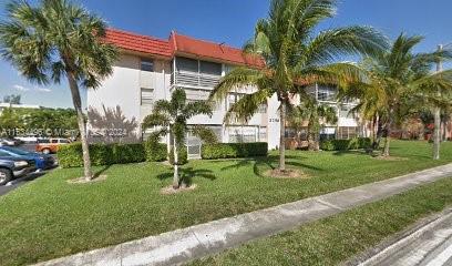 Front view of a multi-story building with red roof and palm trees.