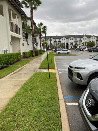 Outdoor parking area adjacent to a residential building with cars parked.