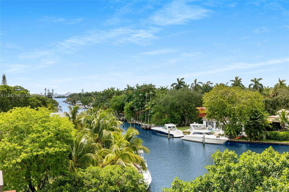 Panoramic view of a canal lined with boats and surrounded by lush greenery.